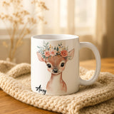 White mug with a deer design and floral crown on a textured surface