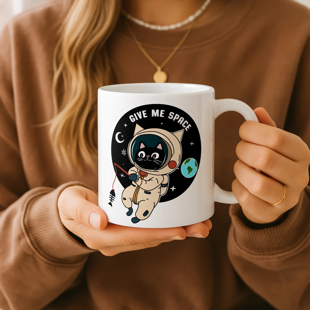 Person holding a white mug with an astronaut design and 'Give Me Space' text.